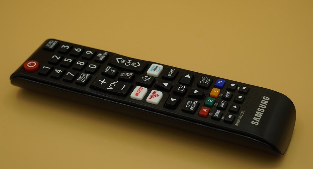 Samsung UE50TU7020 TV's black remote resting on yellow background