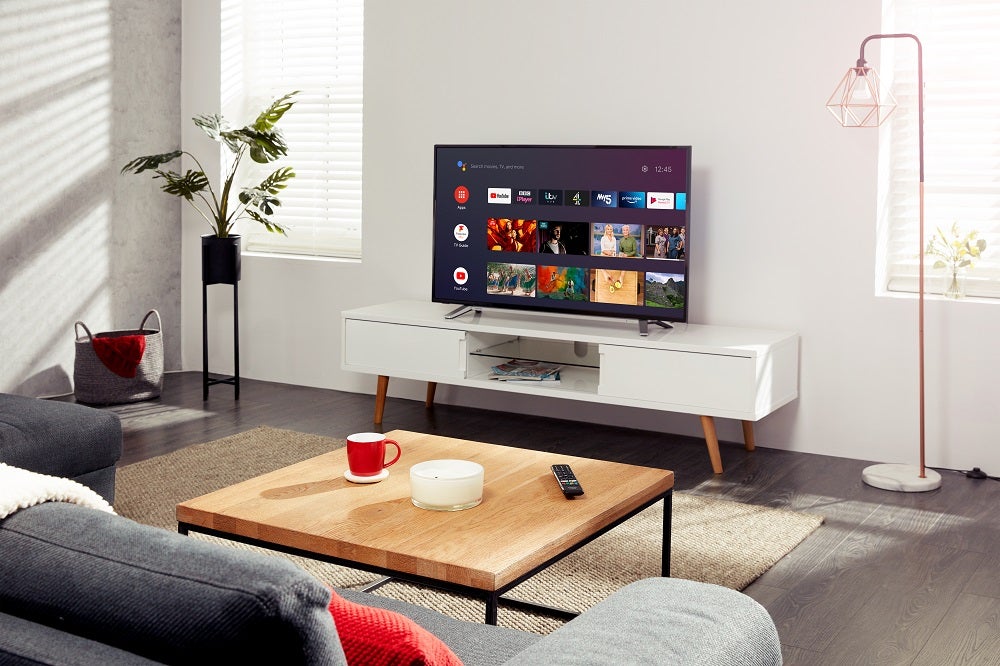 A black and silver Toshiba UA2B 4K TV standing on a white table in a living room