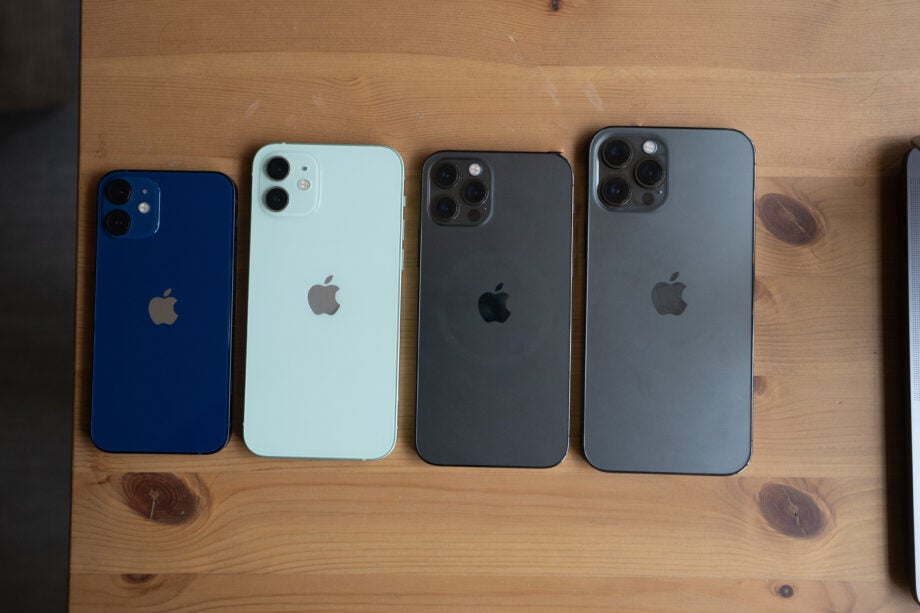 Four iPhones laid facing upside down a table aligned vertically, view from top