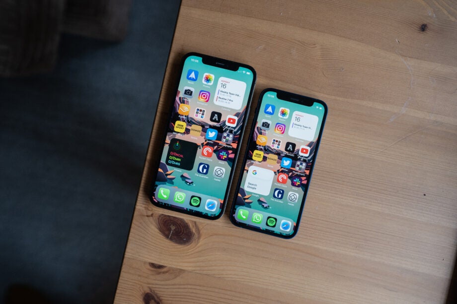 Two iPhones laid on a table aligned vertically, view from top, both displaying home screen