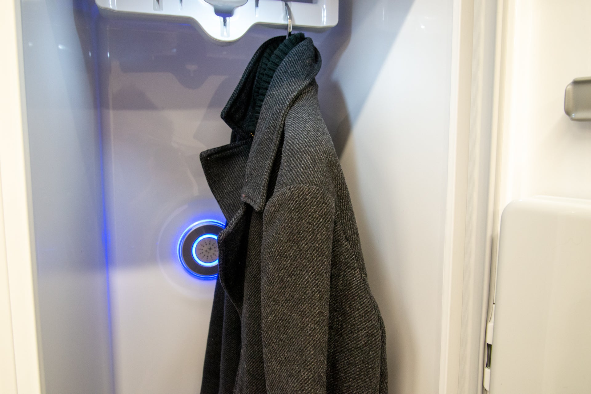 A black coat hanging inside LG styler