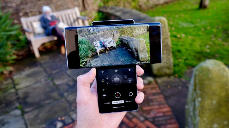 A LG Wing smartphone held in hand, camera opened on one screen and buttons to click picture on the other