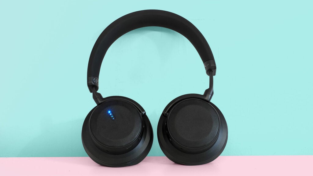 Black BNX100 headphones standing against a blue wall