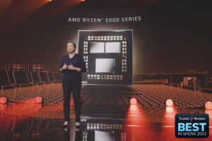An old women standing on a stage with AMD Ryzen 5000 series displayed behind her on a big screen