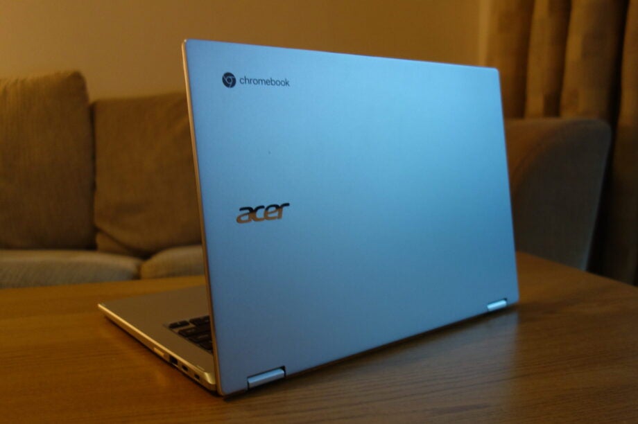 Back left view of a silver Chromebook Spin 514's back panel standing on a wooden table