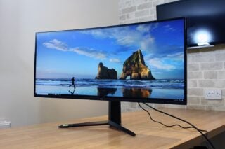 Front right angled view of a black LG UltraGear 38GN950 monitor standing on a wooden table