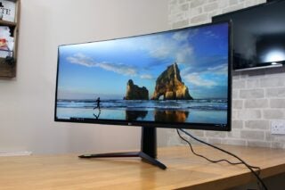 Front right angled view of a black LG UltraGear 38GN950 monitor standing on a wooden table