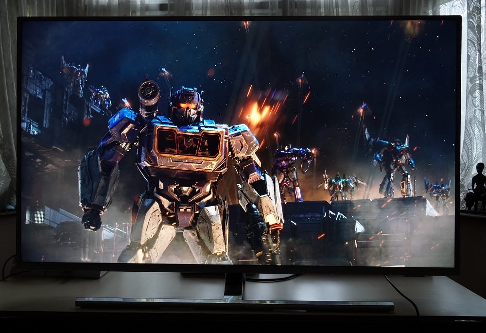 A black Philips 50PUS8545 TV standing on table, displaying a scene from Bumblebee