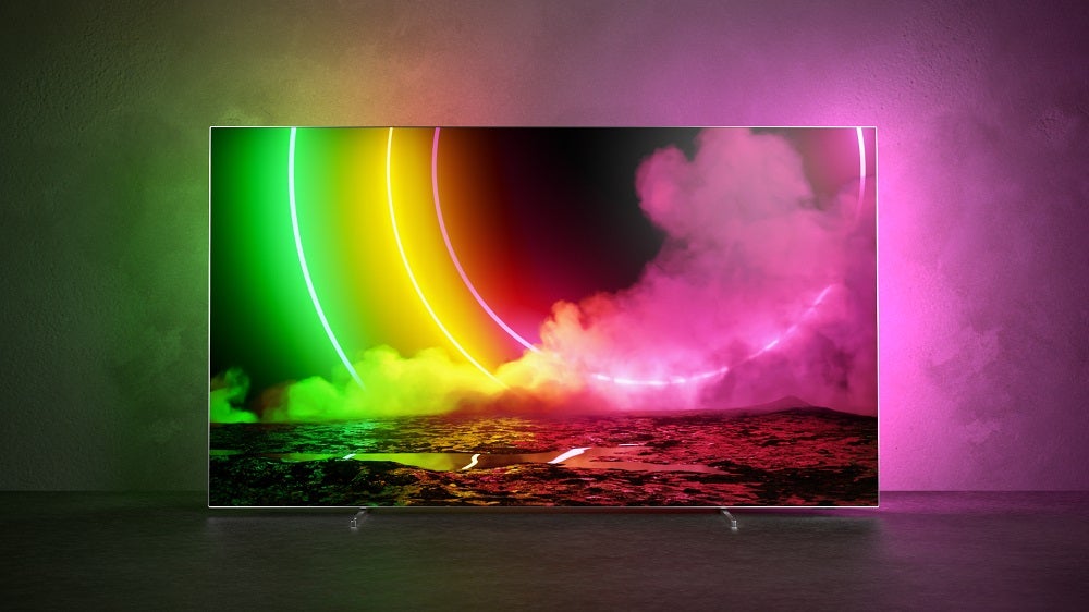 A Philips OLED806 standing on a table, displaying a colored wallpaper with its light escaping from TV to room
