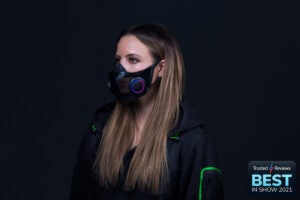 A beautiful lady in black-green outfit, wearing a black mask, standing in black background