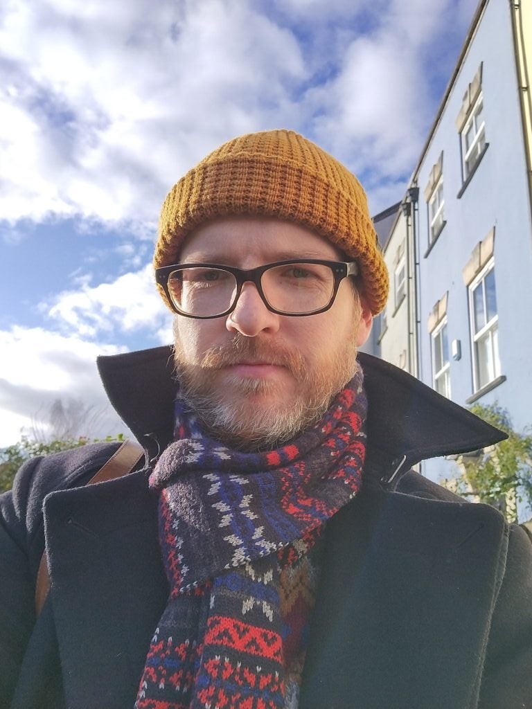 Selfie of a bearded man wearinng coat, a scarf and a yellow cap