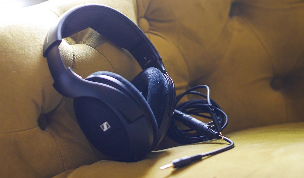 Front left view of a black Sennehsier HD560S standing against a yellow cushion