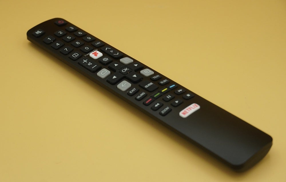 TCL-55C715K TV's black remote resting on a yellow background