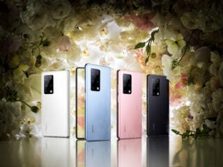 five Huawei Mate X2 devices stood on reflecting glassy surface facing a nicely blended colored roses