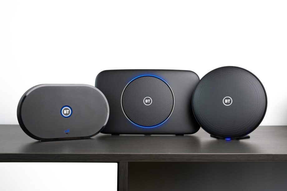 Three different shaped black bluetooth speakers standing on a wooden table with BT written at the center of each speaker