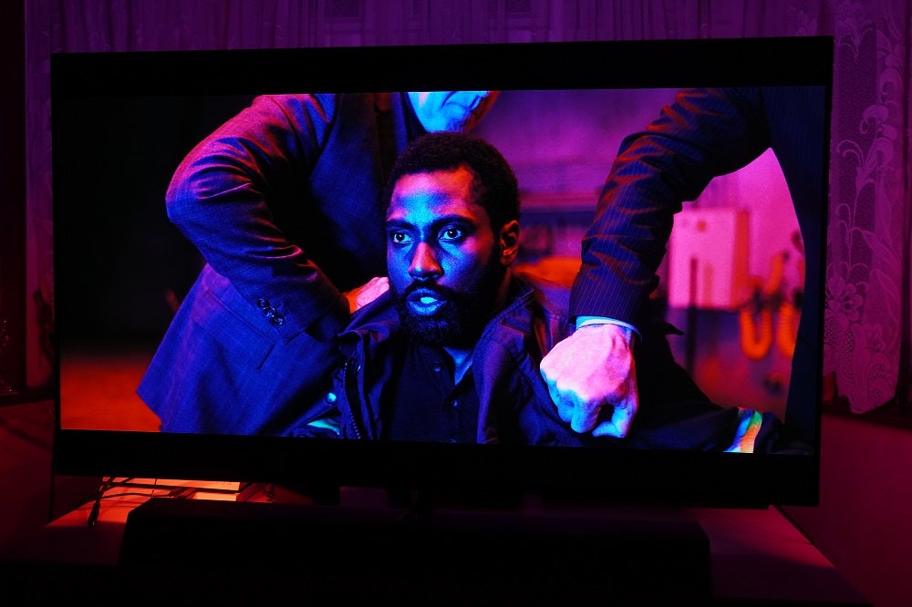 A black Philips OLED935 TV standing on a table, displaying a scene from a movie to showcase Ambilight