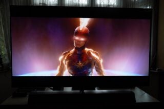 A black Philips OLED935 standing on a table, displaying a scene from Captain Marvel