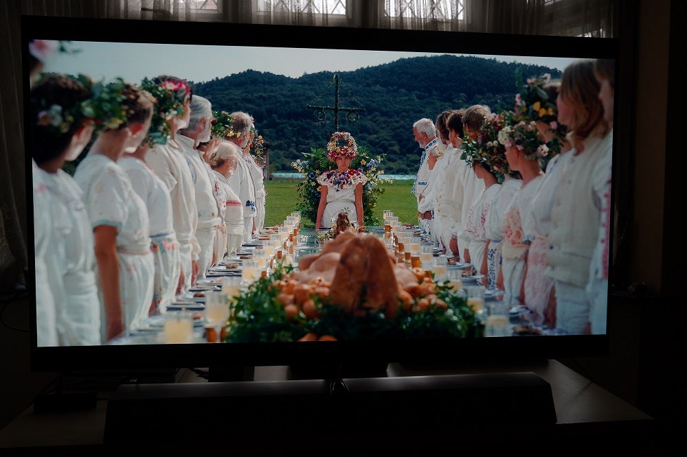 A scene from Midsommar in 4K Dolby Vision on the Philips 55OLED935A black Philips OLED935 standing on a table, displaying a scene from Midsommar