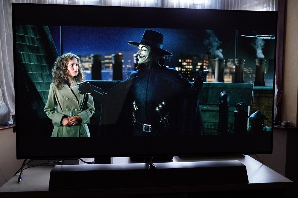 A black Philips OLED935 standing on a table, displaying a scene from Vendetta