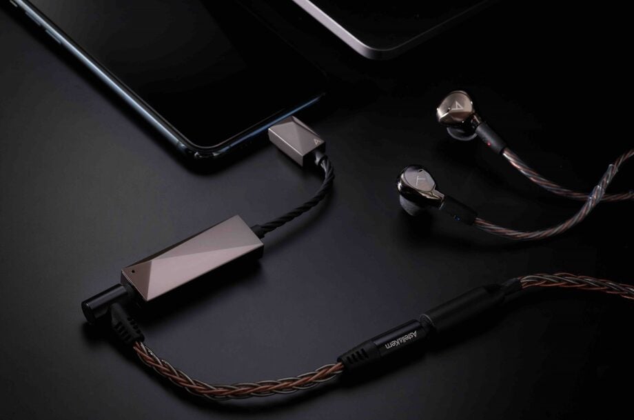 A black and brown Astellkern USB dual DAC cable attached to a phone on black background