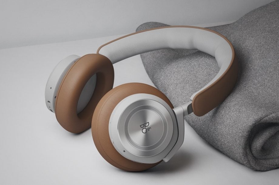 White and brown BO Beoplay HXTimber headphones resting on a white table