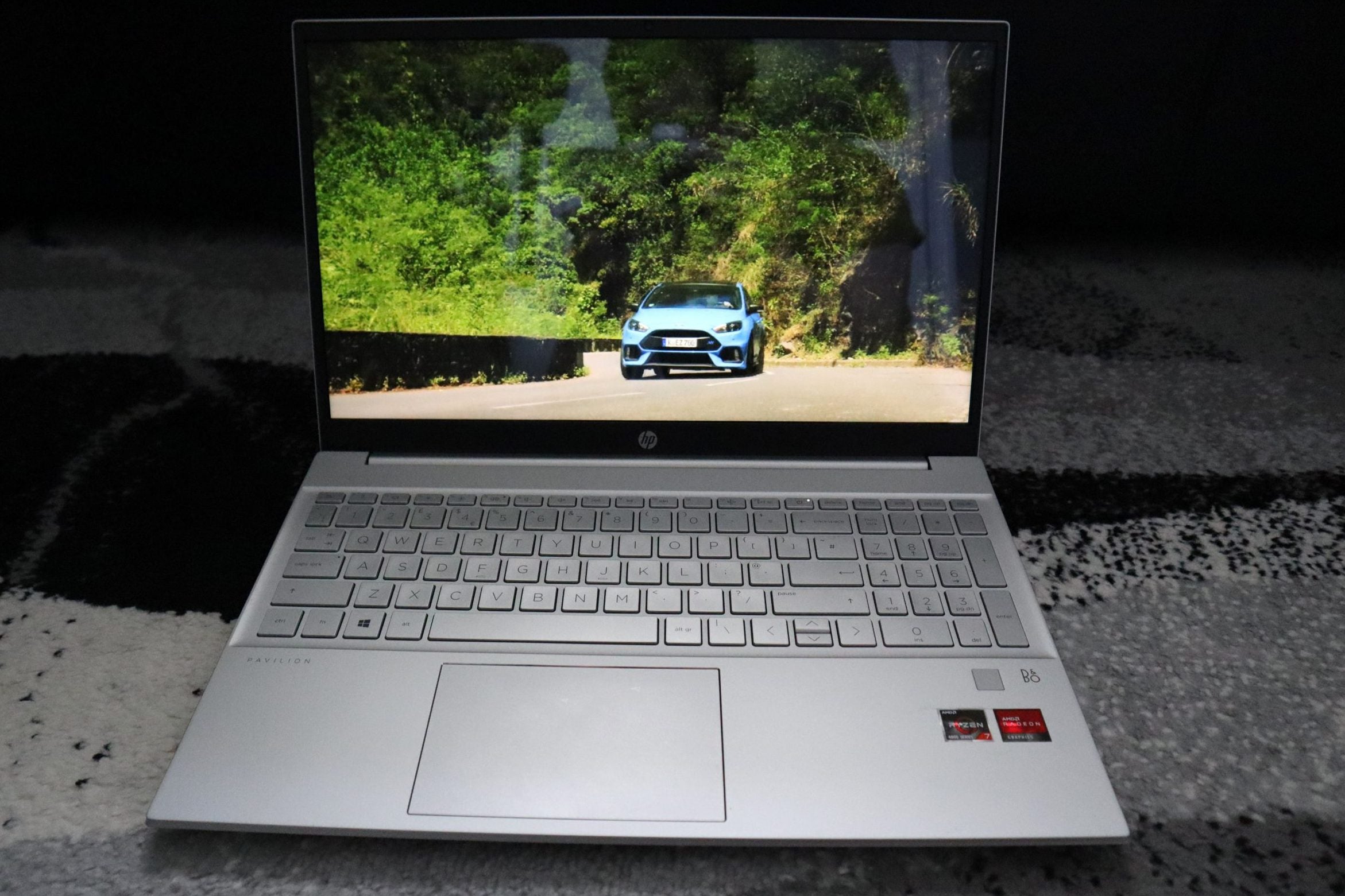 A black and silver HP Pavillion 15 laptop, displaying a car on road