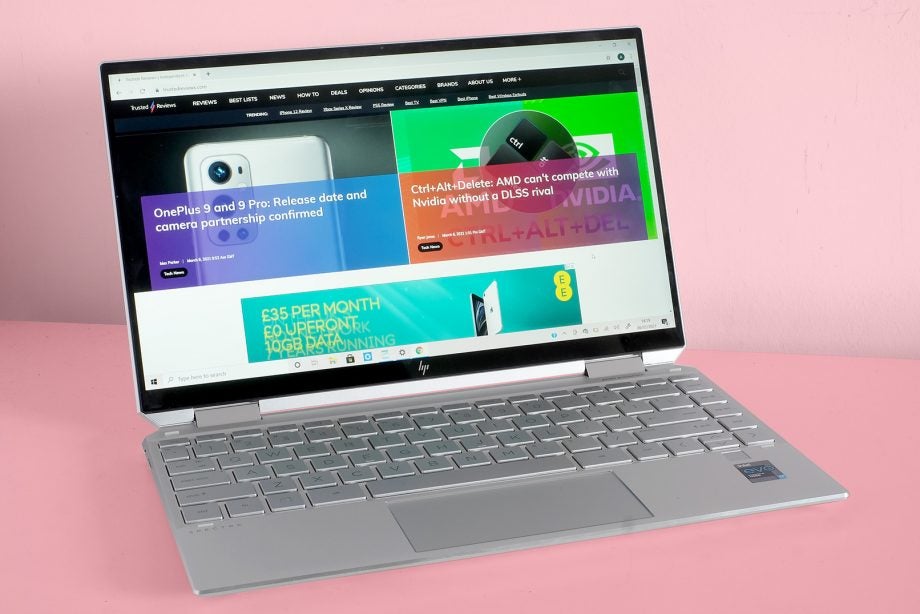 A silver HP spectre X360 laptop on pink background, displaying articles on Trusted reviews