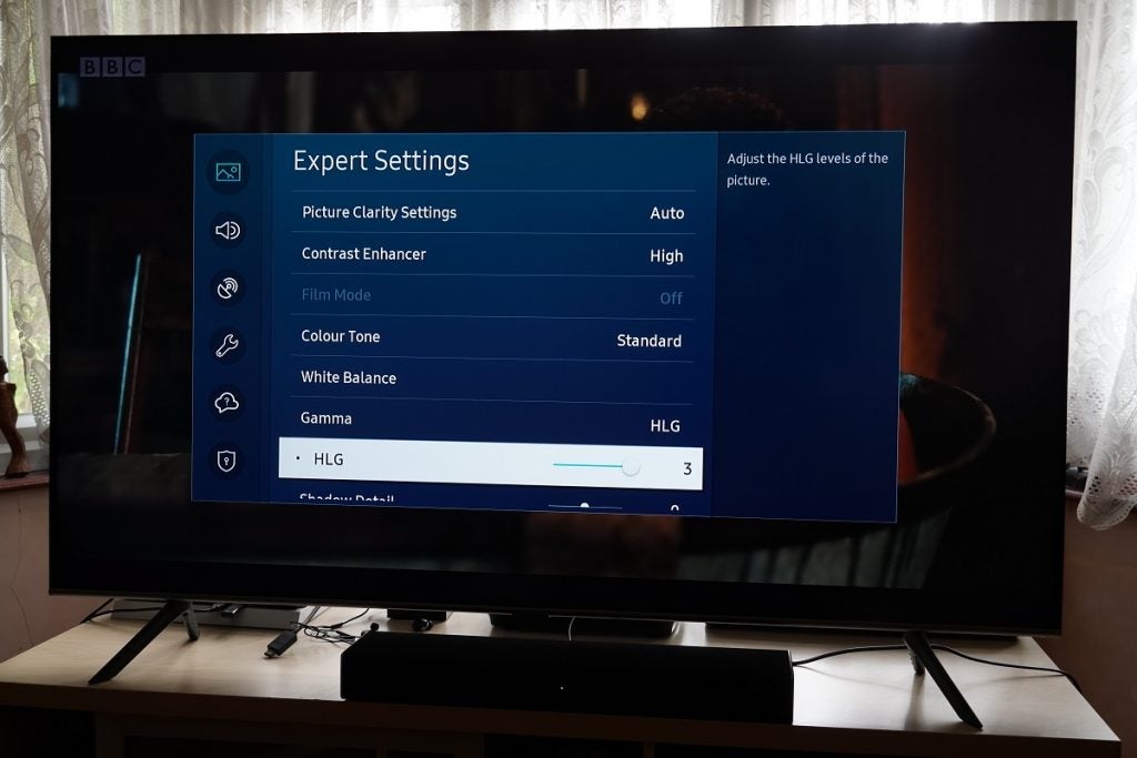 A black Samsung Q65T TV standing on a table, displaying HLG settings on expert settings menu