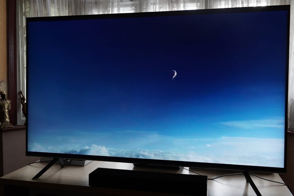 A black Samsung Q65T TV standing on a table, displaying a scene from The Aeronauts