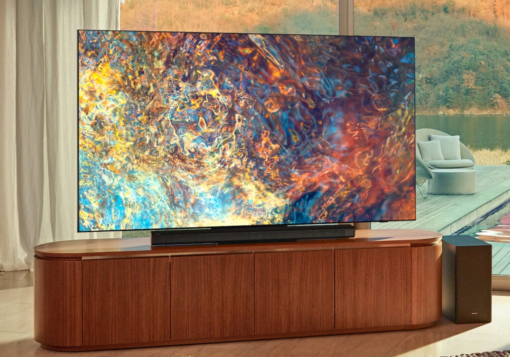 wide screen TV siting fit on well designed TV table with speaker in the side and attractive wallpaper in the background