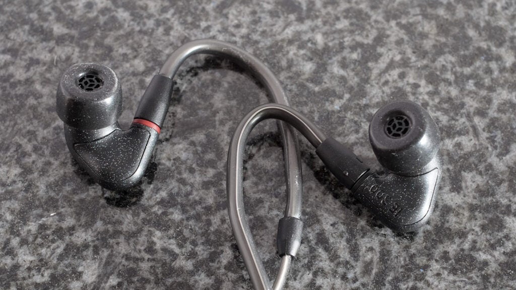 Ear hook design of Sennheiser IE 300Gray and black earphones resting on black backround, front side view