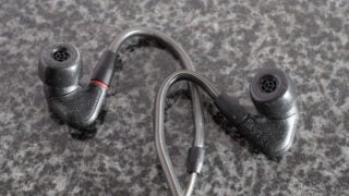 Gray and black earphones resting on black backround, front side view