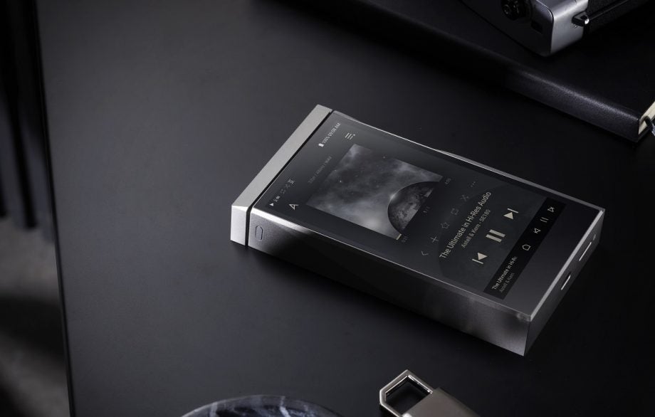 A silver and gray A&K SE180 music player laid on a black table