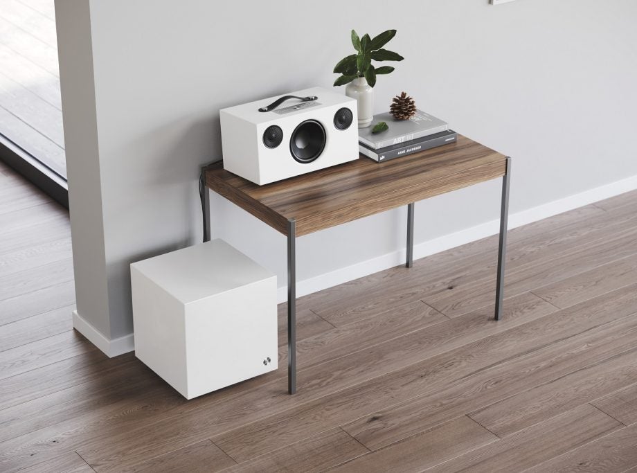 A white Active subwoofer SW5 Audio speaker kept on a wooden table in white room with wooden floor