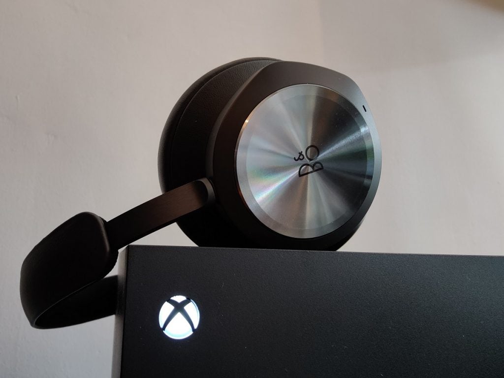 Beoplay Portal on top of Xbox Series XBO Beoplay black headphones resting on a black XBOX