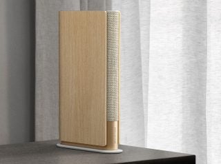A wooden finish Beosound Emerge speaker standing on a table