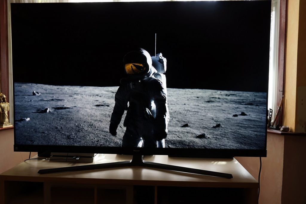 A black Hisense 65U8Q standing on a table, streaming  a scene from First Man movie