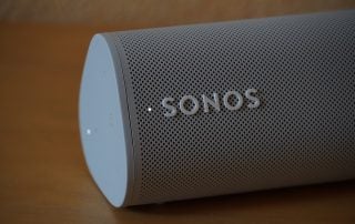 Top left side view of a white Sonos Roam speaker laid on a table