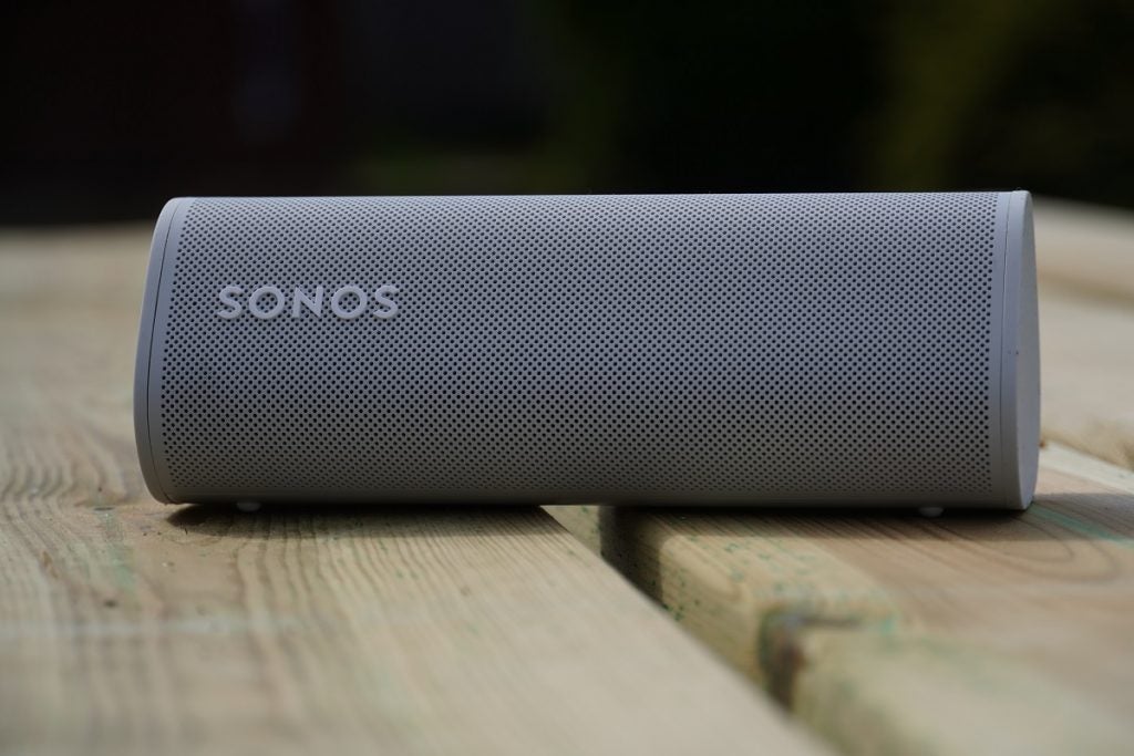 Sonos Roam on garden tableClose up image of a white Sonos Roam speaker laid on a wooden table