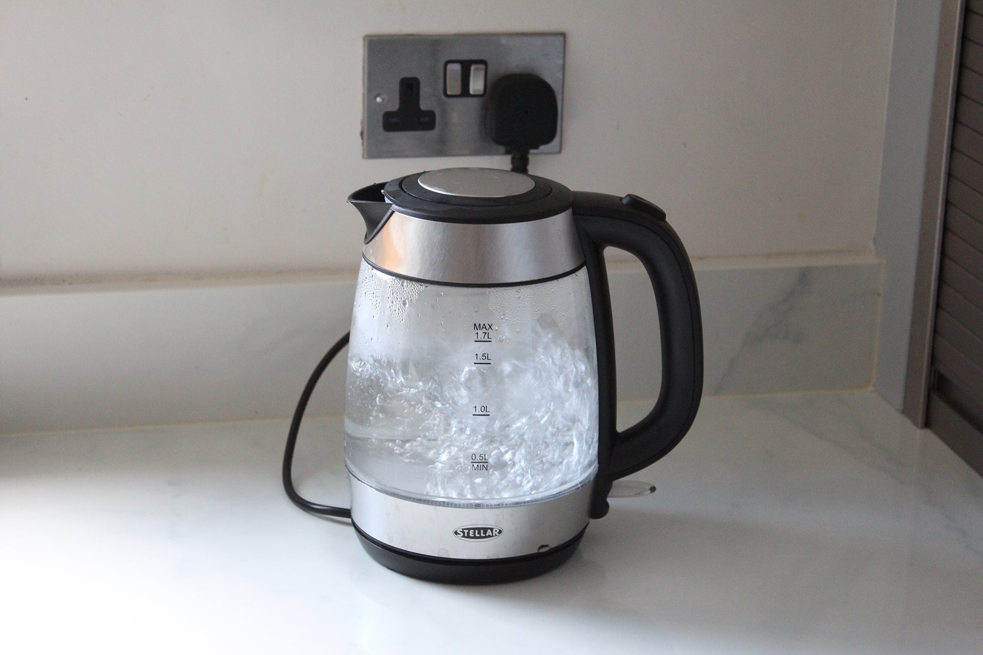 A black and silver Stellar SEA35 electric glass kettle plugged in with ice filled inside