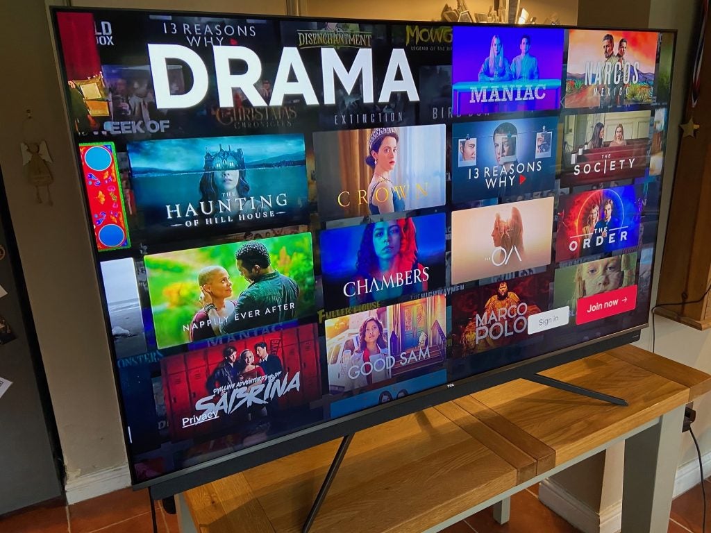 The TCL 65C815K on a standTCL65C815 TV standing on a wooden table, displaying drama series