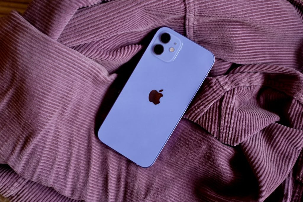 A purple iPhone placed upside down on a purple pink cloth, view from top