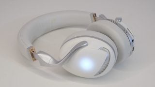 Bottom left side view of silver and wite Iris 7 headphones resting on a white background