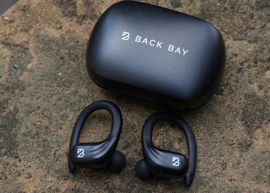 Black Bay's runner 60 wireless earbud's black case resting on ground with earbuds resting below, view from top