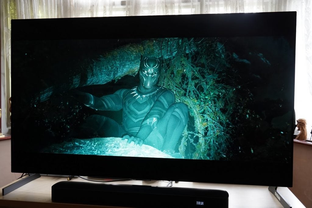 LG G1 OLED TV playing Black Panther, displaying black panther sitting on a tree and light from somewhere is making him visible in the dark night