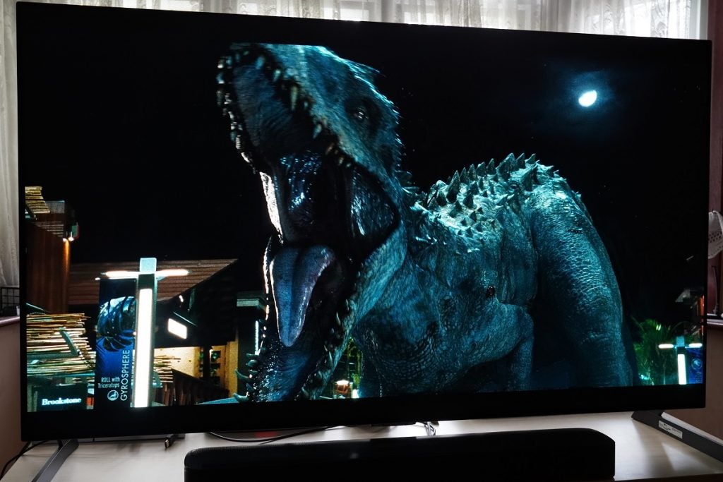 LG G1 OLED TV playing Jurrasic World, displaying  a dinodsaur roaring and moon in the sky