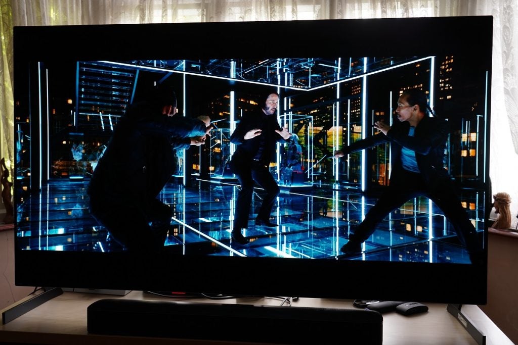 LG G1 OLED TV playing a movie, displaying  three man standing on a glass floor in a fighting positon