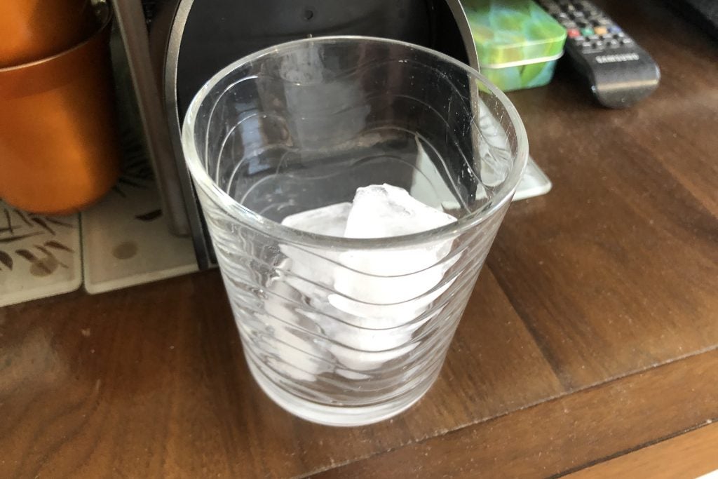 A glass of ice under a Nespresso original machine