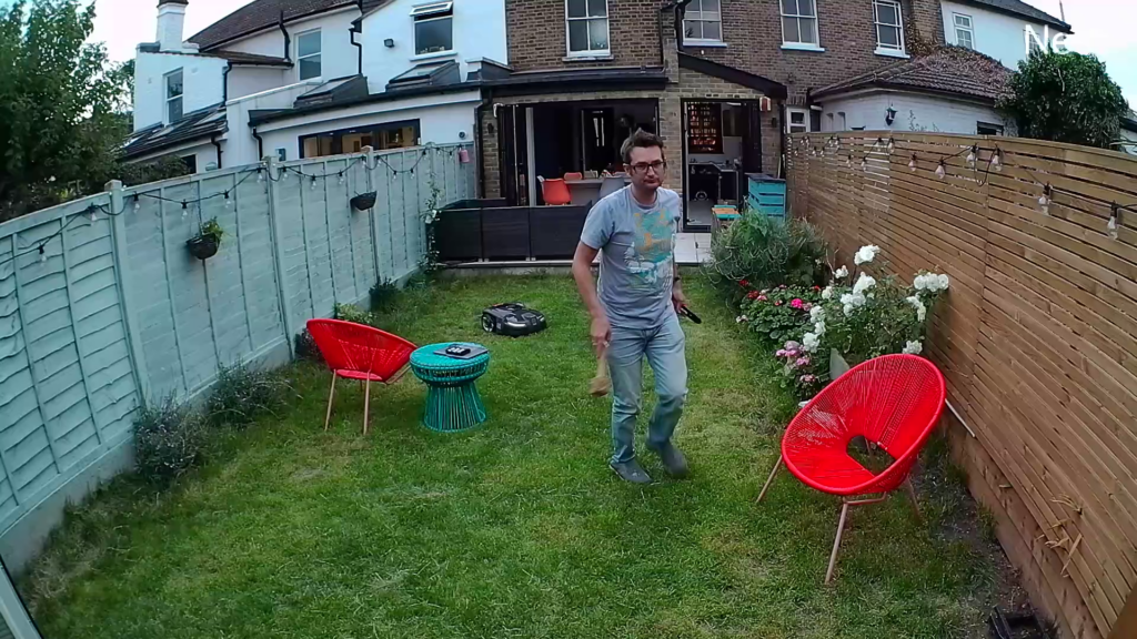 View from Nest Cam of man in garden with red chair and houseMan walking in backyard captured by outdoor Nest Cam