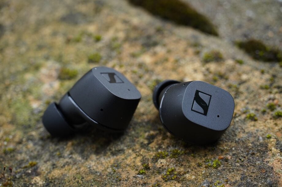 Sennheiser CX True Wireless earbuds on a stone surface.